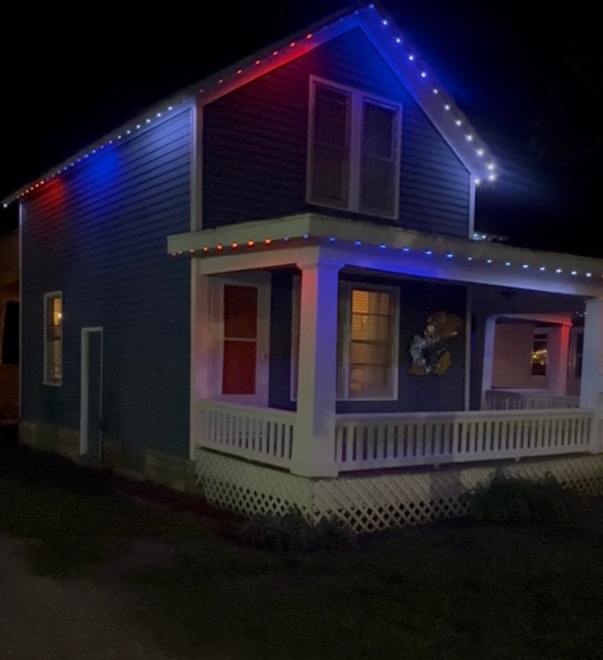 Permanent Christmas lights in red, white, and blue on a two-story home in Lawrence, Kansas by First Response Exterior Lights